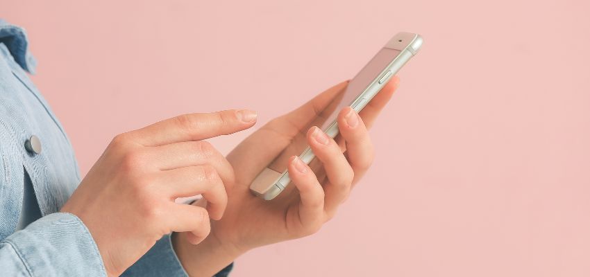 Vue rapprochée d'une personne tenant un téléphone portable et utilisant une application de signature adaptée aux téléphones portables.