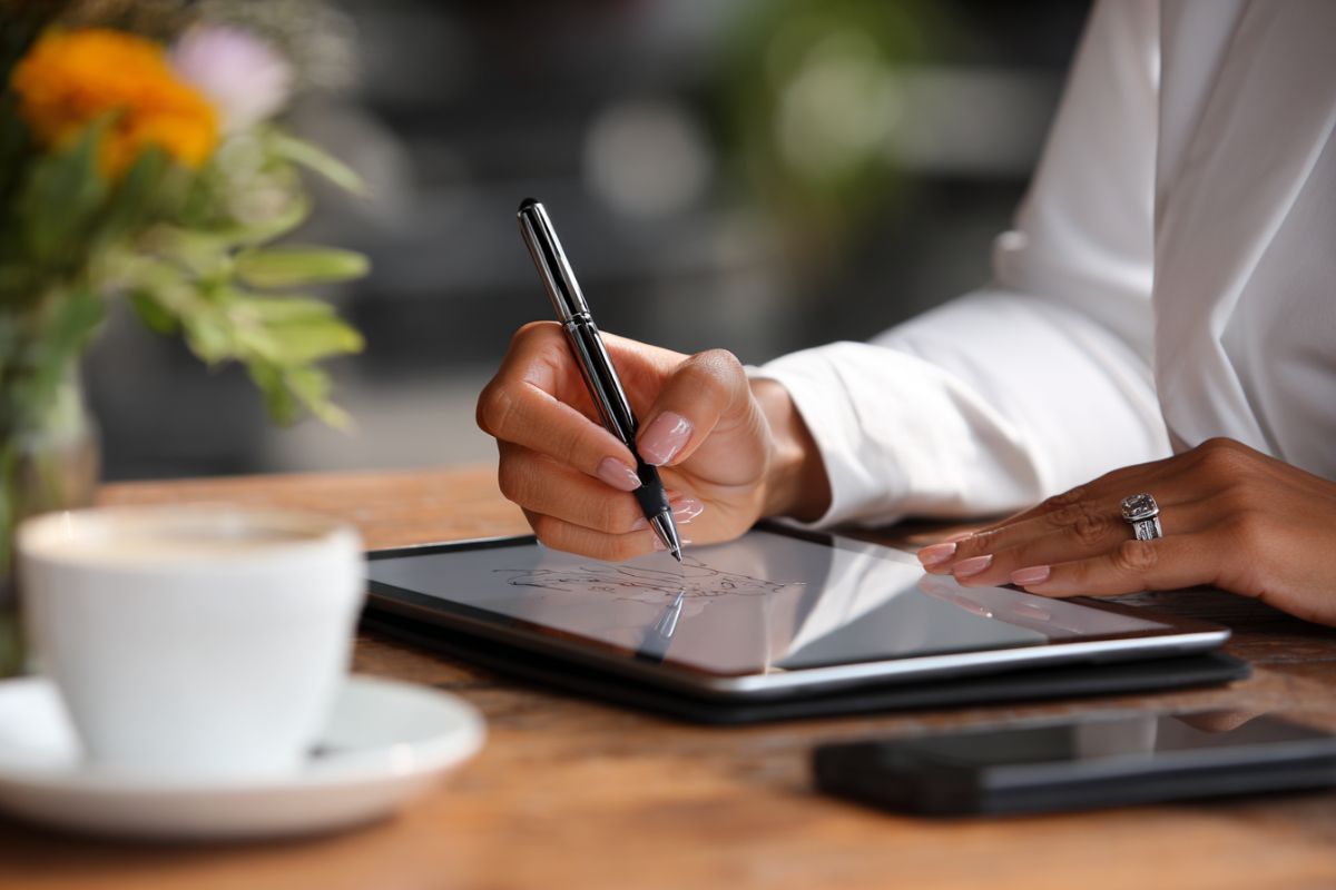 Close-up of a person e-signing a document on a tablet through paperless contract solutions.